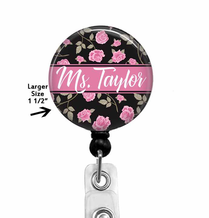 Pink flowers on a black background  with a name in the center.  The badge top is affixed to a retractable reel.  The top can be permanently attached to the reel or made to swap out designs.